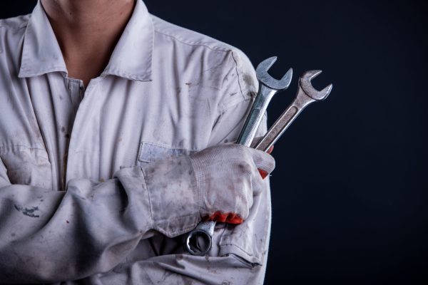 Car mechanic wearing a white uniform stand holding wrench isolat Car mechanic wearing a white uniform stand holding wrench isolated on gray background with copy space.